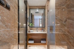 Une salle de bain moderne avec un mur en marbre, une douche à parois de verre, un meuble-lavabo en bois et un grand miroir.