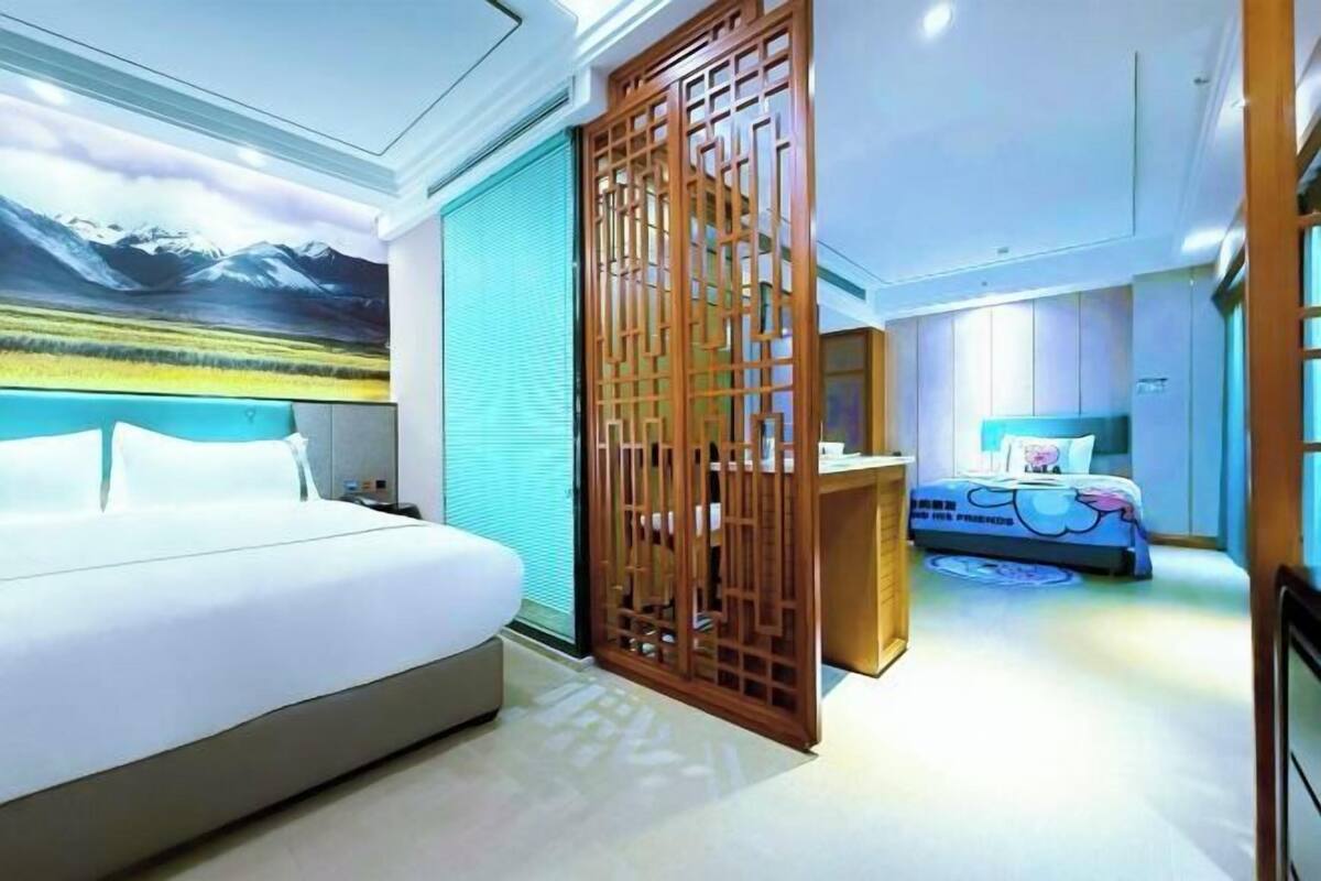 A hotel room with a large bed, a desk, a chair, and a view of mountains through a window.