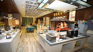 Un hall d’hôtel moderne avec un comptoir d’accueil central, un espace salon et un mur décoratif agrémenté d’une horloge.