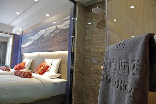 A hotel room with a bed, pillows, a towel, and a shower area. - Putong Hotel (Xining)