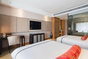 A hotel room with a large bed, a desk, a chair, a TV mounted on the wall, and a glass partition. - Putong Hotel (Xining)