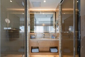 A modern bathroom with a glass shower enclosure, a marble vanity, and a large mirror. - Putong Hotel (Xining)