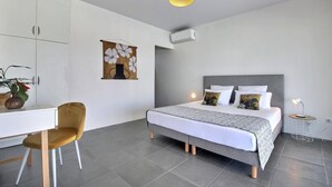A modern bedroom with a bed, bedside table, chair, and artwork. - Villa Macaré - Two Bedroom Villa, Sleeps 5 (Le Marin)