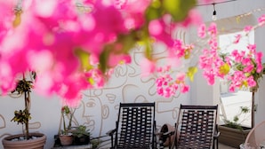 A patio area with two wooden chairs, potted plants, and a wall with a face mural. - Los Murmullos Casa Boutique Campeche (Campeche)