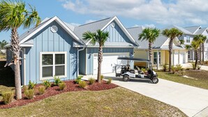 A residential building with a garage, a golf cart, and palm trees. - WindMark | Golf Cart | Pet Friendly | In-Law Suite (Port St Joe)