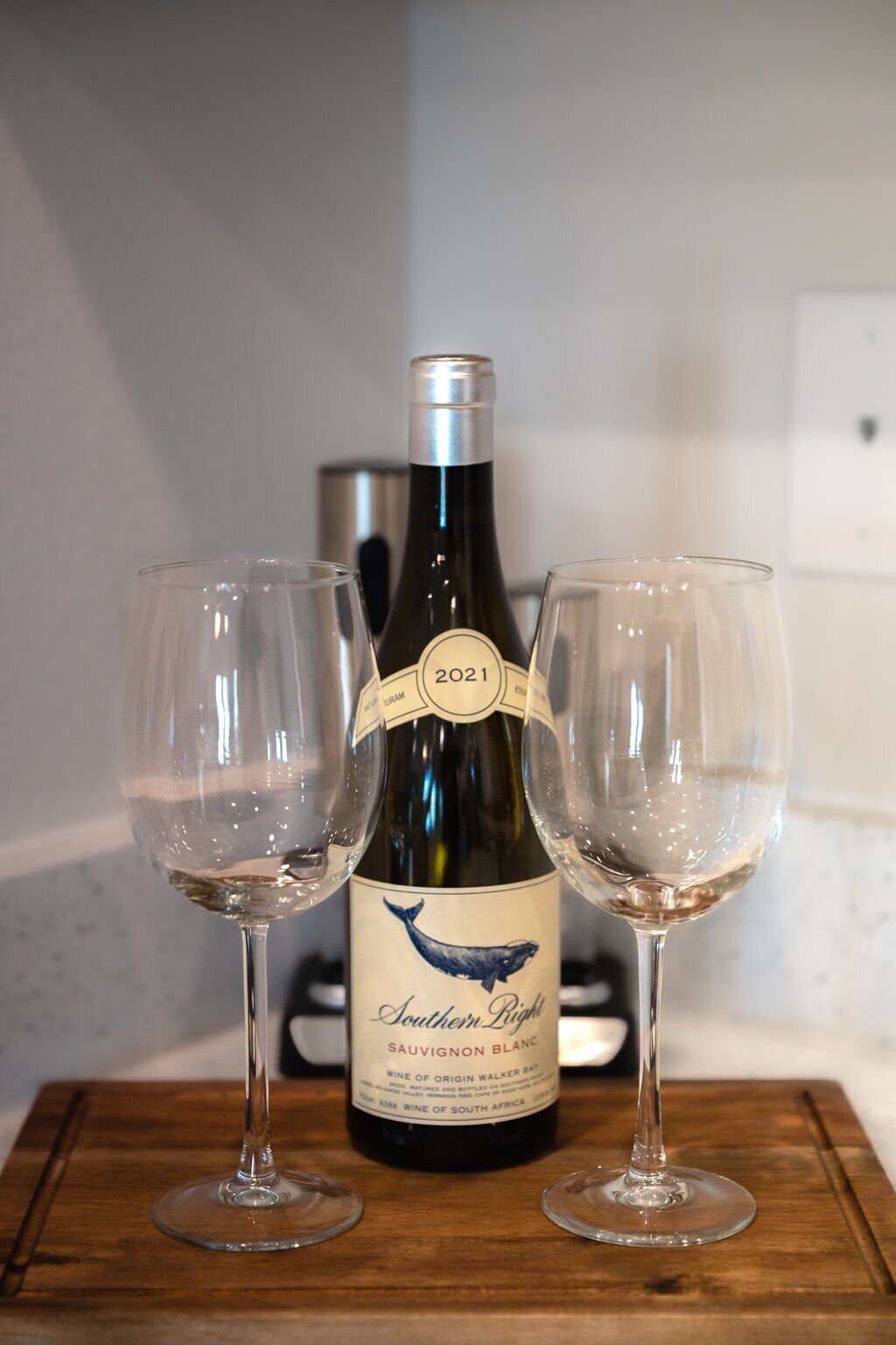 A bottle of wine with two glasses on a wooden surface.