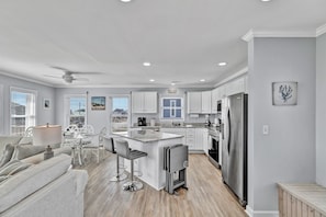 A modern kitchen with white cabinets, a central island, and a stainless steel refrigerator.