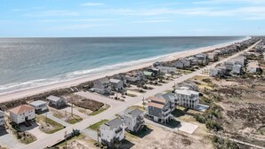 Une zone résidentielle côtière avec des maisons le long de la plage, un ciel dégagé et une mer calme.