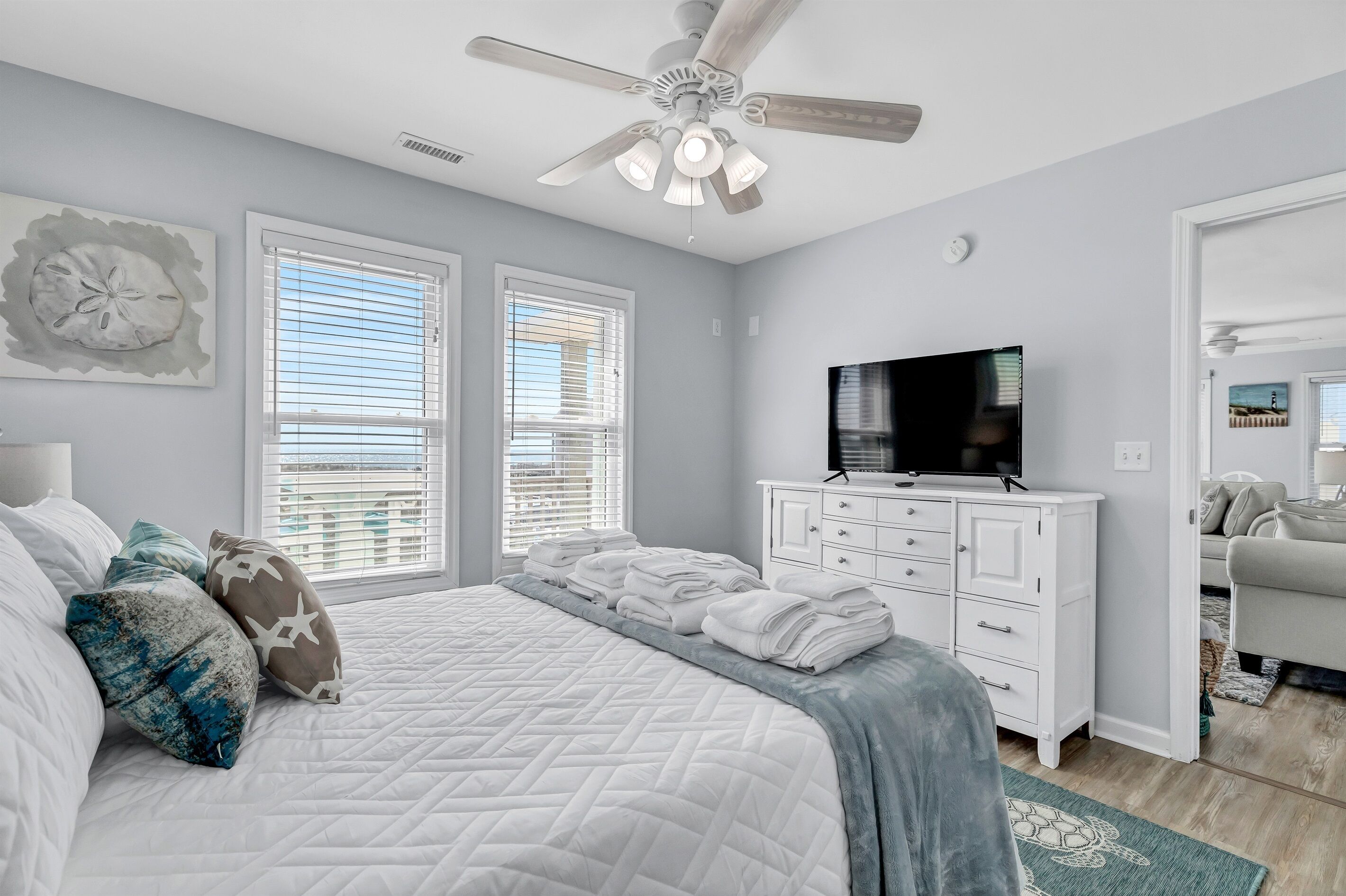 A bedroom with a bed, a ceiling fan, a TV, and a dresser.