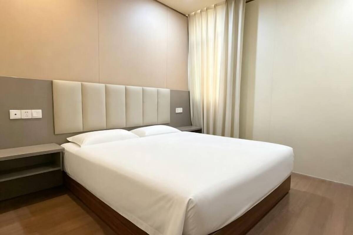 Une chambre d’hôtel moderne avec un grand lit, une table de chevet et une tête de lit intégrée.