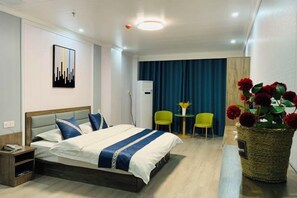 Een hotelkamer met een bed, nachtkastje en een kleine tafel met stoelen.