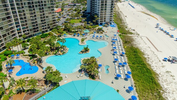 A resort with multiple swimming pools, a beach, and high-rise buildings.