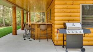 A covered outdoor area with a wooden grill station and bar stools. - Near Memorial Park: Lake Arbutus Vacation Rental (Hatfield)