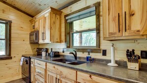 A wooden cabin kitchen with a double sink, stainless steel appliances, and wooden cabinets. - Near Memorial Park: Lake Arbutus Vacation Rental (Hatfield)