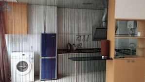 Eine kleine Küche mit Waschmaschine, Kühlschrank und einer Glasablage.