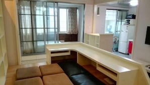 Ein kompakter Wohnbereich mit Sofa, Sitzbank, Küchenzeile und einer Schiebetür aus Glas.