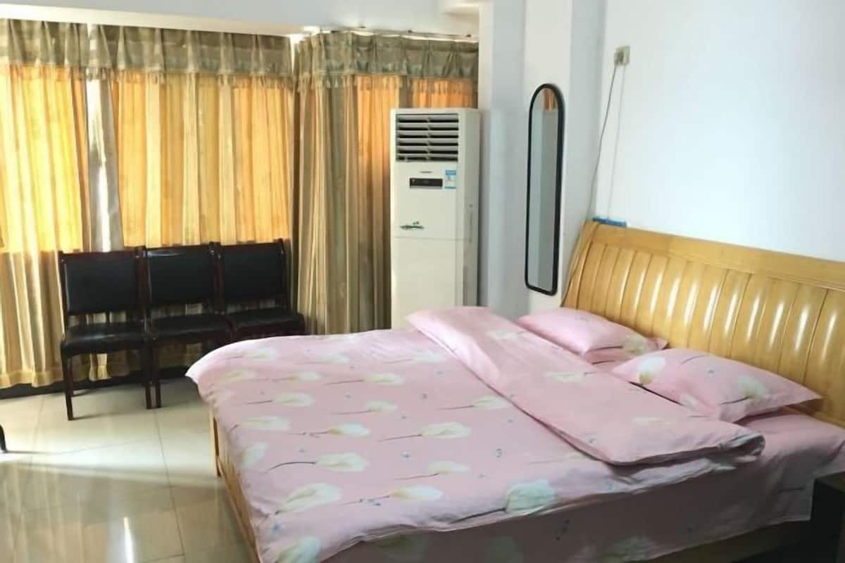 A bedroom with a bed, a chair, a mirror, and an air conditioning unit.