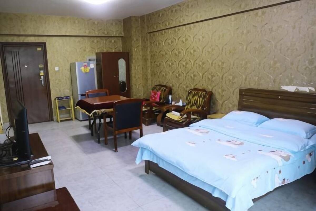A bedroom with a bed, a desk, a chair, a television, and a wardrobe.