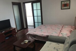 Ein Schlafzimmer mit Bett, Fernseher, einem kleinen Tisch und einer Couch.