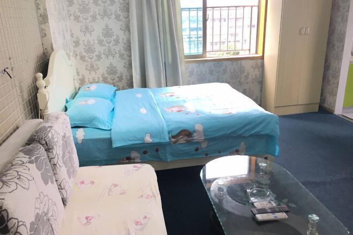 Ein Schlafzimmer mit Bett, Sofa, Glastisch und einem Fenster mit Blick.