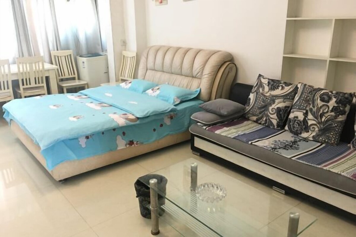 Ein Schlafzimmer mit einem Bett, einem Schlafsofa, einem Glastisch und einem Sessel.