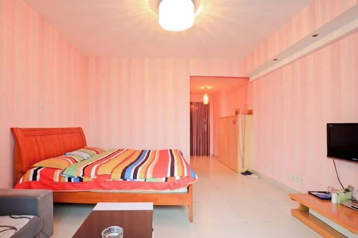 A bedroom with a bed, a TV, a desk, and a chair.