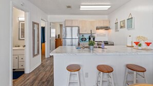 Una cocina moderna con una isla central, armarios de madera, electrodomésticos de acero inoxidable y una zona de bar con taburetes.