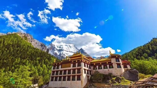 A traditional building with a symmetrical facade, set against a backdrop of a clear blue sky and a snow-capped mountain. - Yading Paradise Inn (Daocheng County)