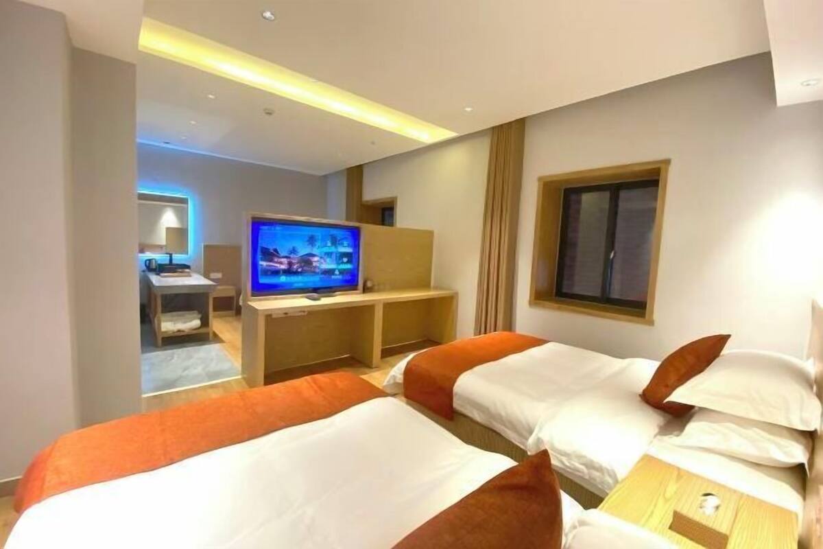 A hotel room with two beds, a TV, and a desk with a chair.
