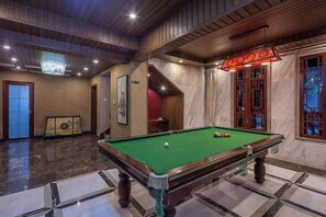 Een pooltafel in een ruimte met een houten plafond en een rood verlichte lamp.