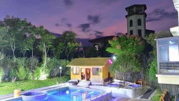 Una piscina con una pequeña casa y una torre al fondo.