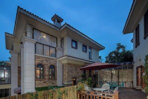 Una casa de dos pisos con un patio que tiene mobiliario exterior y una valla de madera.