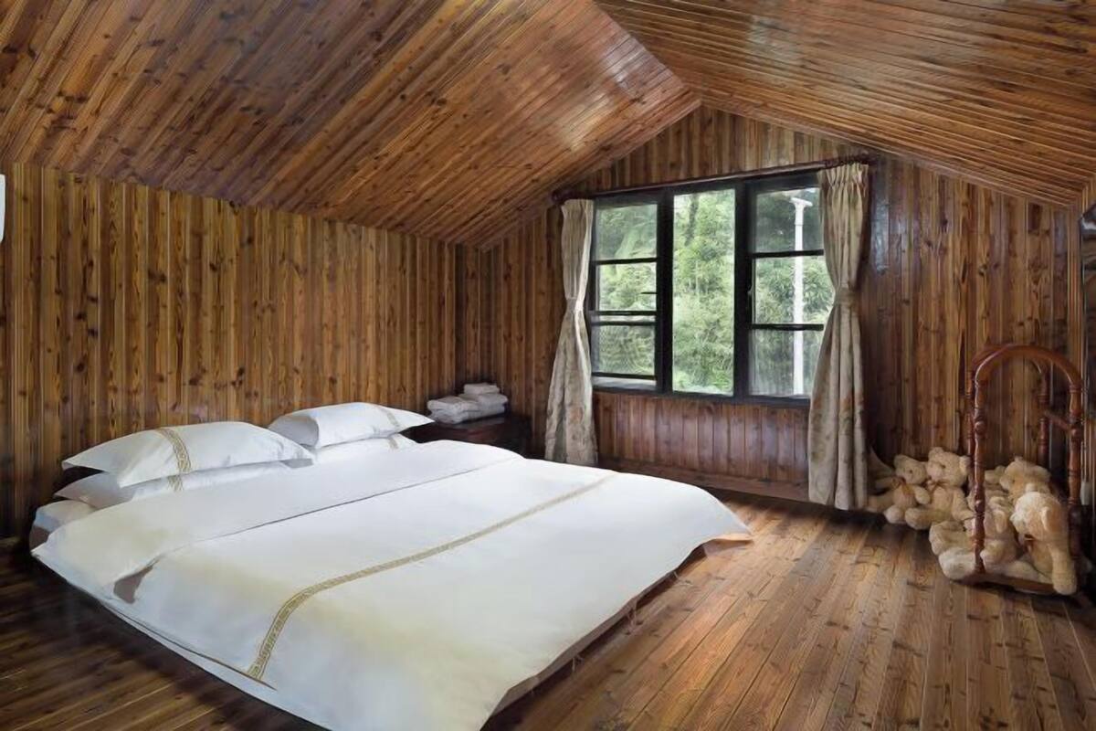 Une pièce dans un chalet en bois, avec un lit, une fenêtre et une chaise.