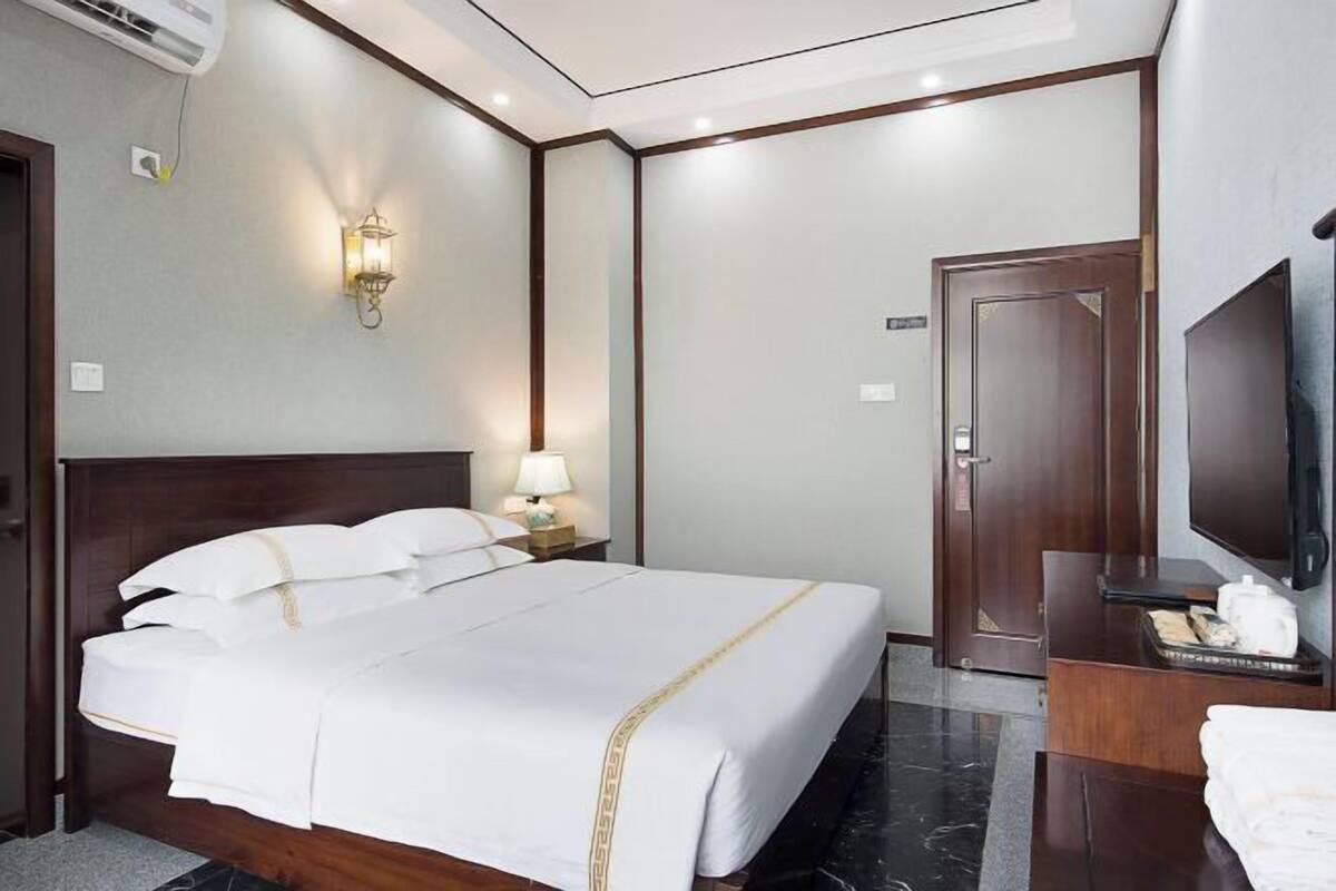 Une chambre d’hôtel avec un grand lit, une télévision, un bureau et une armoire.