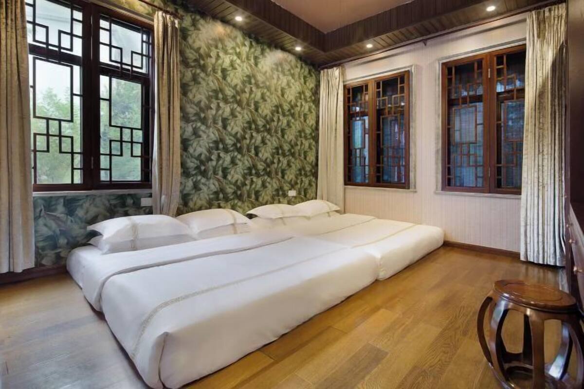 Une chambre avec un lit, un plancher en bois et des fenêtres de style traditionnel.