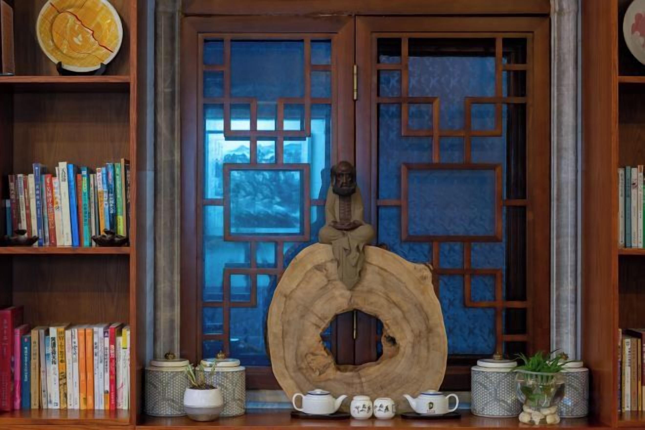 A traditional room with a wooden door, a large wooden sculpture, and bookshelves filled with books.