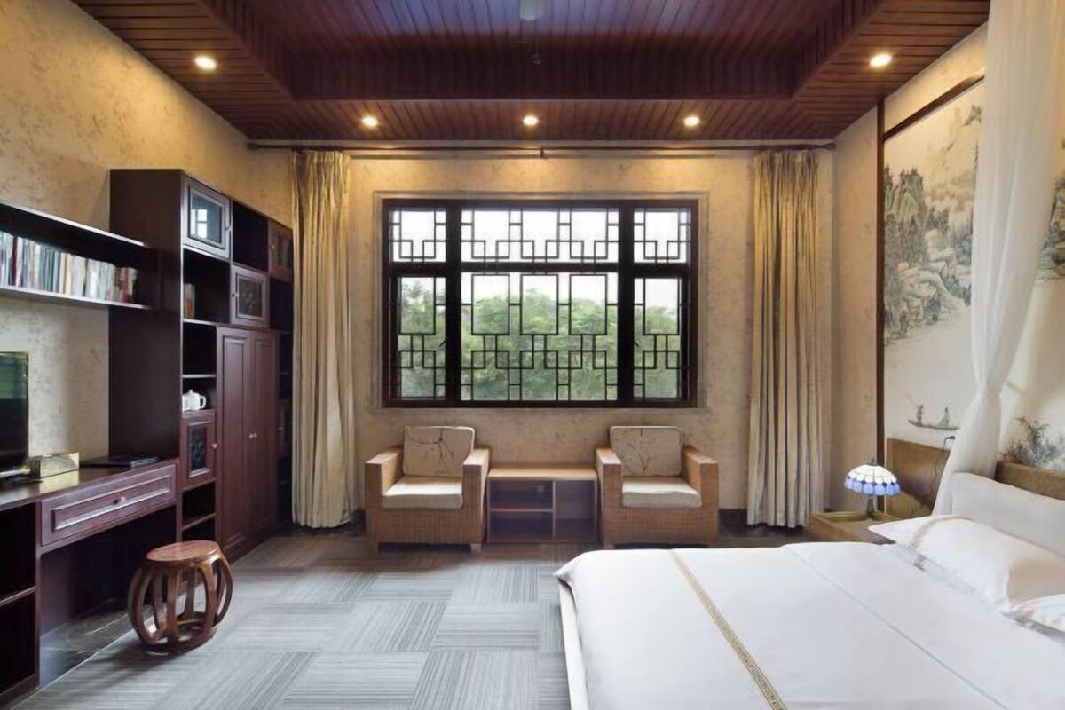 Une chambre à coucher avec un lit, deux chaises, un bureau et une bibliothèque.