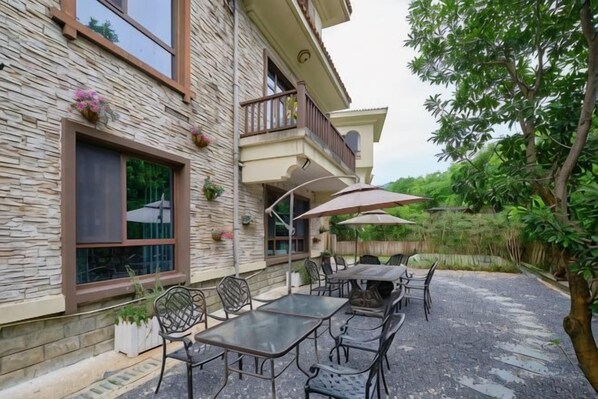 A stone building with a balcony, outdoor seating, and potted plants.