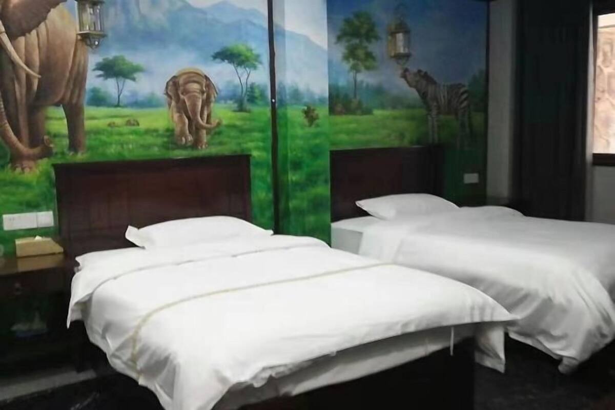 Une chambre d’hôtel avec deux lits, une fresque représentant des animaux sauvages et une fenêtre avec des rideaux.