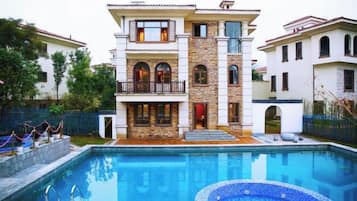Un edificio de varios pisos con una piscina delantera.