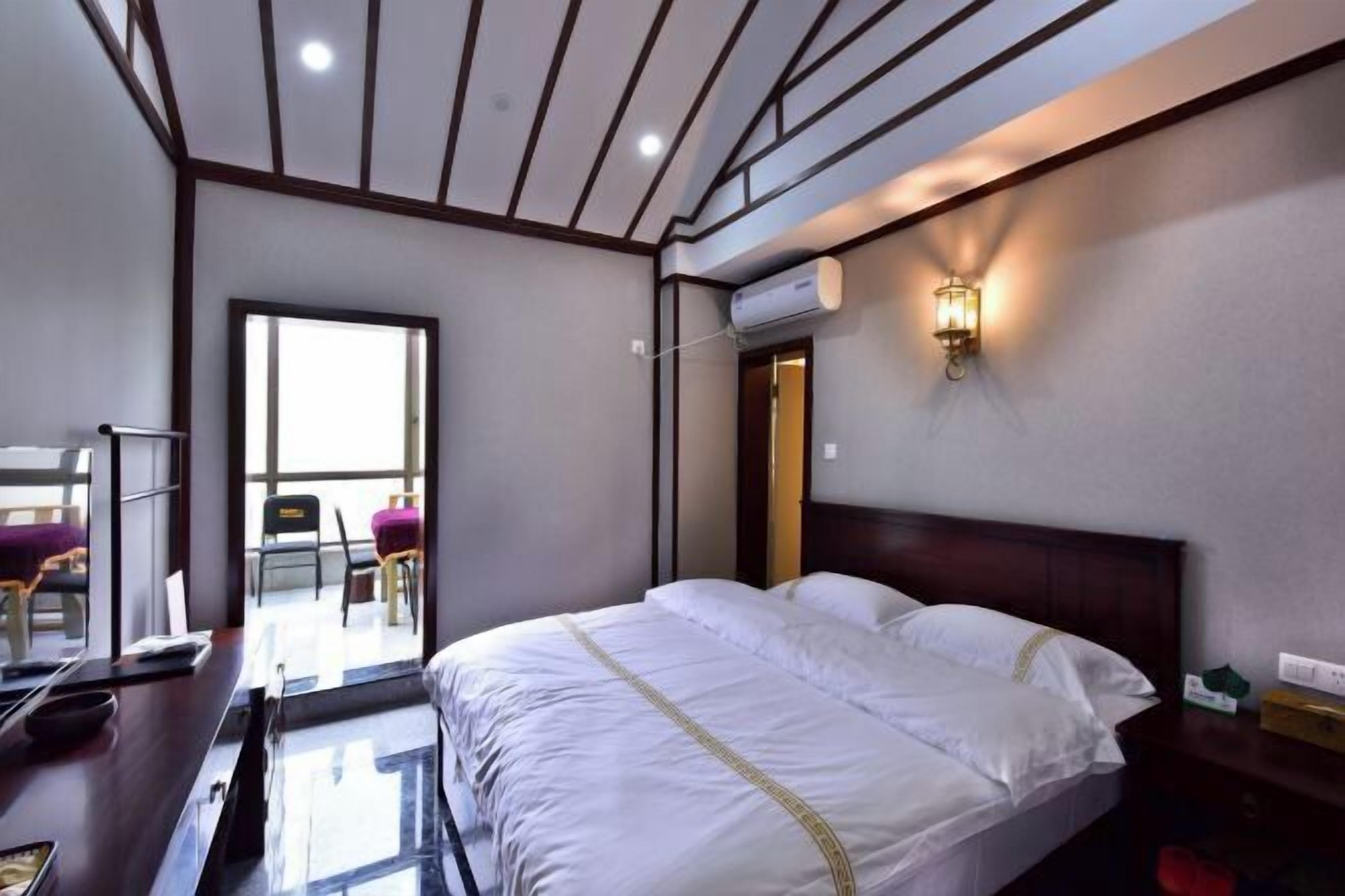 Una habitación de hotel con cama, escritorio, silla y ventana.