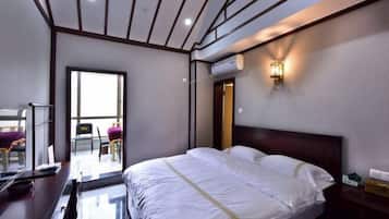 A hotel room with a bed, a desk, a chair, and a window.