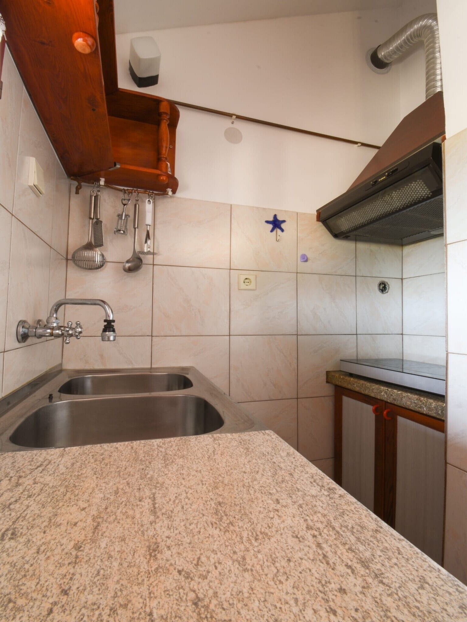 A kitchen with a double stainless steel sink, wooden cabinets, and a granite countertop.