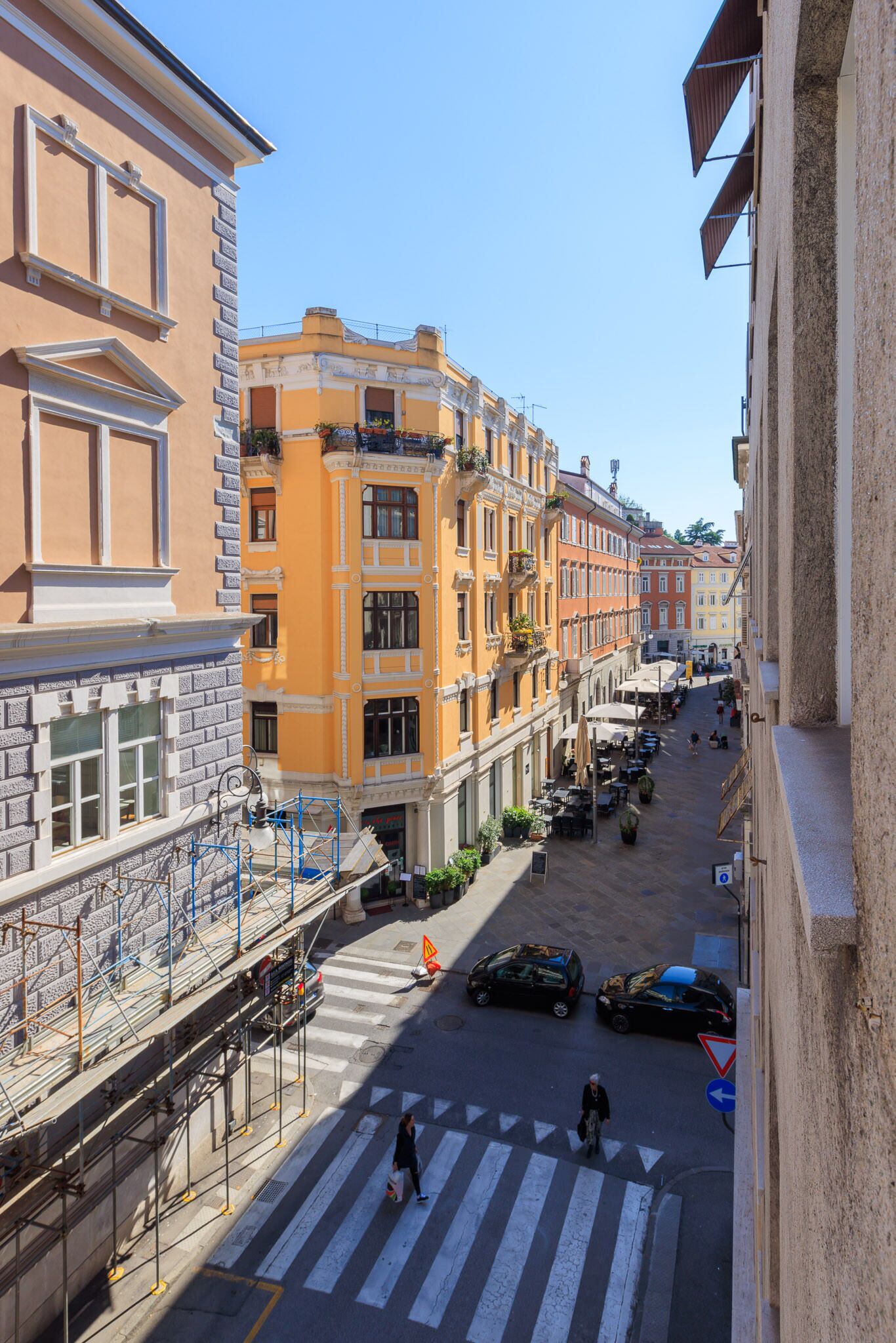 A street view with buildings, a pedestrian crossing, and cars.