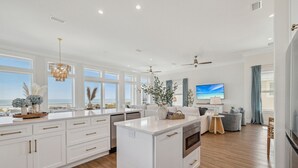 A spacious kitchen with white cabinetry, a central island, and a view of the ocean. - Tides Beach House: Beachfront New Build- Sleeps 30, Pet Friendly, Priv. Pool (Cape San Blas)