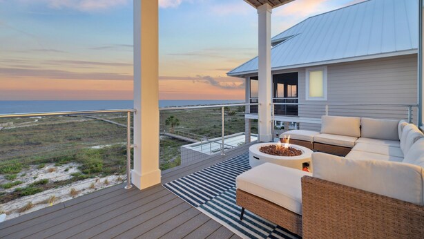 A balcony with a view of the beach, a wicker sofa, and a fire pit. - Tides Beach House: Beachfront New Build- Sleeps 30, Pet Friendly, Priv. Pool (Cape San Blas)