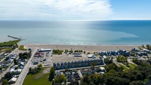 An aerial view of a coastal residential area with a beach, houses, and a pier. - Cozy, spacious family home w/ Arcade! 5 mins from Beach! (Port Stanley)