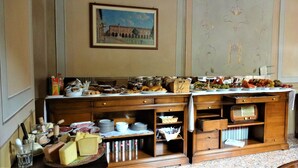A buffet setup with various food items and a painting on the wall. - Albergo Giulia Gonzaga (Sabbioneta)