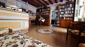 A cozy living room with a fireplace, a large bookshelf, and a floral-patterned sofa. - Albergo Giulia Gonzaga (Sabbioneta)
