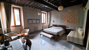 A bedroom with a bed, a chair, a table, and a bench. - Albergo Giulia Gonzaga (Sabbioneta)